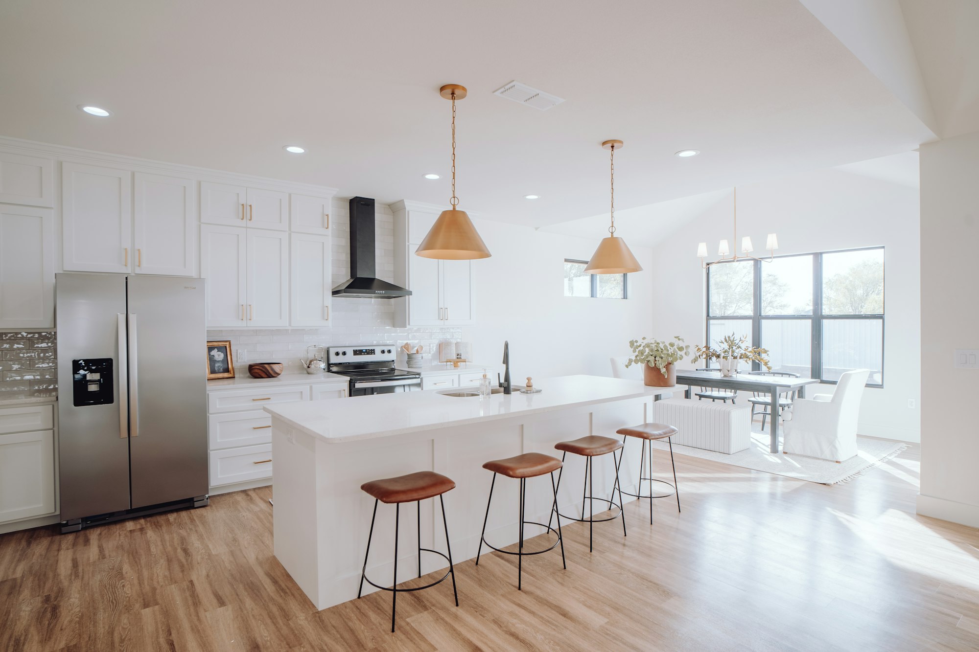 A bright white kitchen with a center island and stools