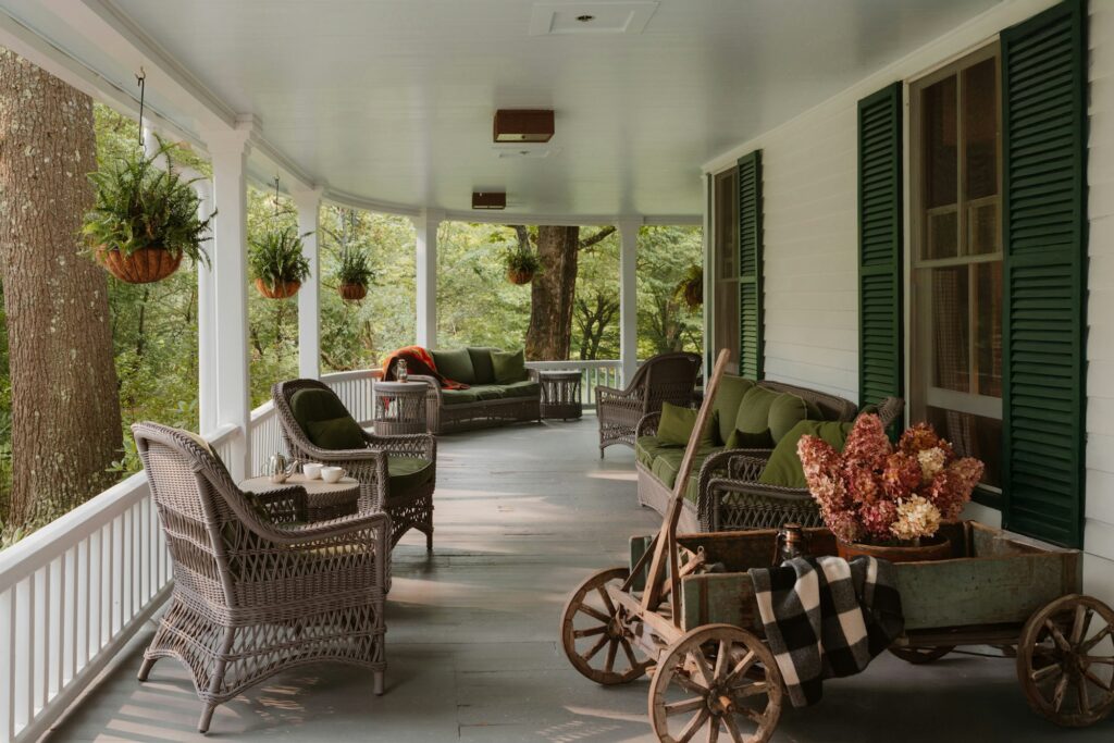 A wide covered porch with wicker chairs and hanging plants
