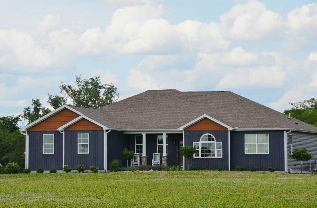 A single-story dark blue home with a green lawn